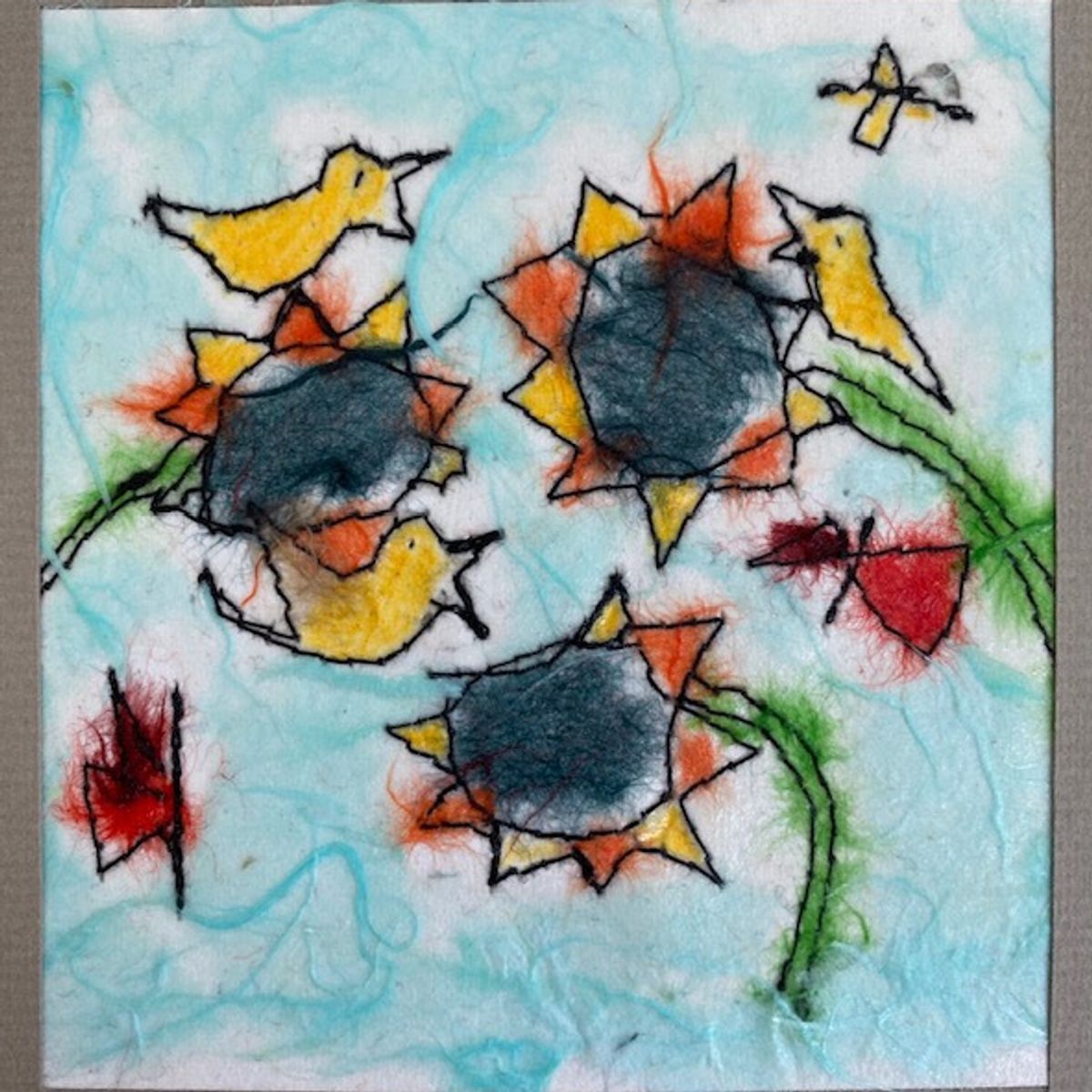 A felted panel on aqua wool, stitched in black outline. Three sunflowers with dense slate centres, yellow birds perched and flying between them, and two deep-red butterflies at the edges.