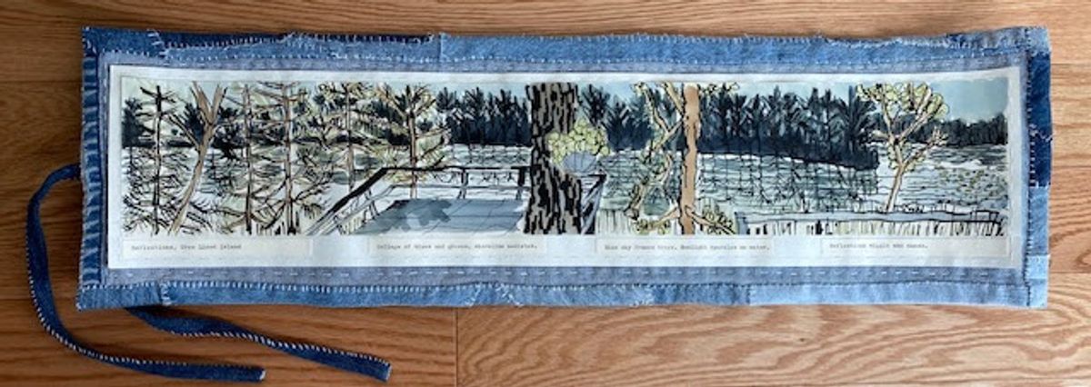 A long horizontal panel bordered in pieced pale denim with fabric ties, lying on oak. Within it, a continuous ink and wash winter landscape: bare trees, a dark treeline, fence posts and flat pale ice.