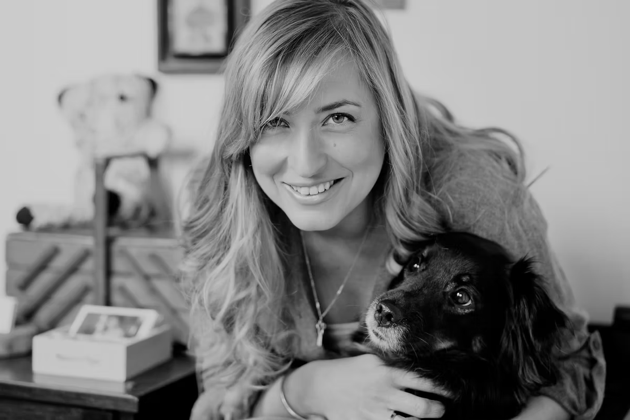 Black and white portrait of designer Rafaela Kalderon smiling, holding a small dog