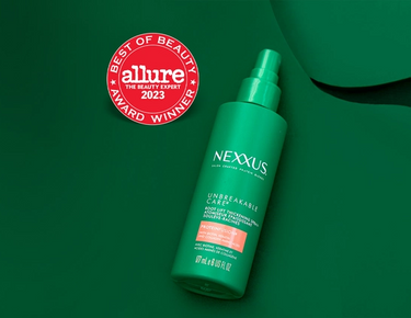 A bottle of Unbreakable Care Root Lift Thickening Spray is shown against a dark green background with the Allure Best of Beauty Award Winner 2023 seal next to it.