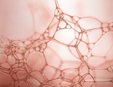 A closeup shot of bubbles is shown against a rose-gold background.