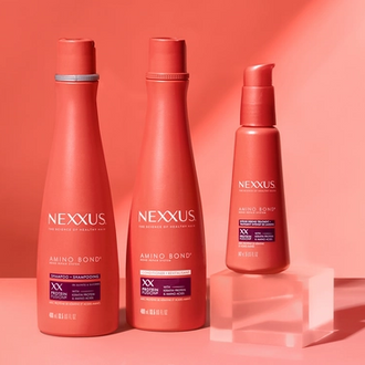 The entire Nexxus Amino Bond Repair System collection and two scientific beakers are shown against a peachy orange background. 