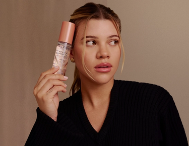 Sofia Richie Grainge is shown posing with her hair styled loosely pulled back with the hair oil product.
