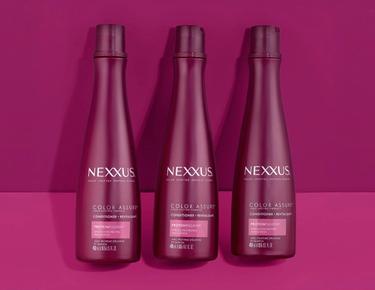 Three bottles of Color Assure Conditioner are shown against a pink background.