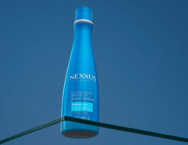 A bottle of Ultralight Smooth Weightless Protection Shampoo is shown against a blue background.​