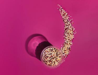 A microscopic view of the various ingredients are shown in a container sitting atop a pink background.