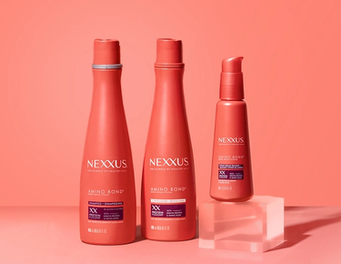 The entire Nexxus Amino Bond Repair System collection is shown against a peachy orange background.