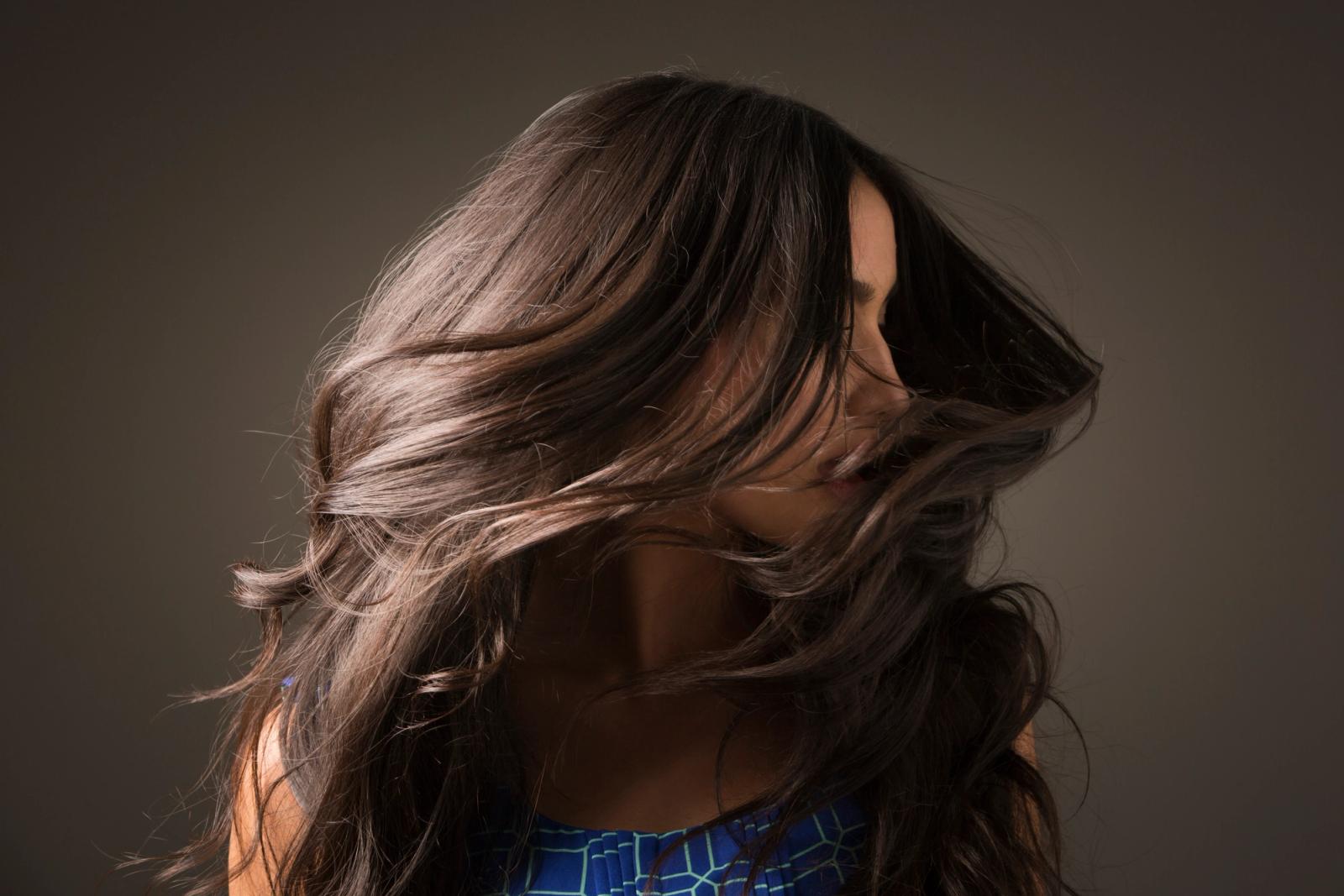 Woman with long dark brown hair at photoshoot, shaking head from side to side.
