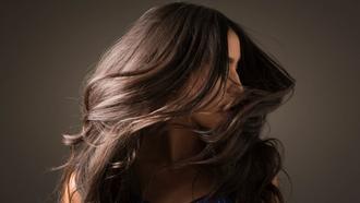 Woman with long dark brown hair at photoshoot, shaking head from side to side.