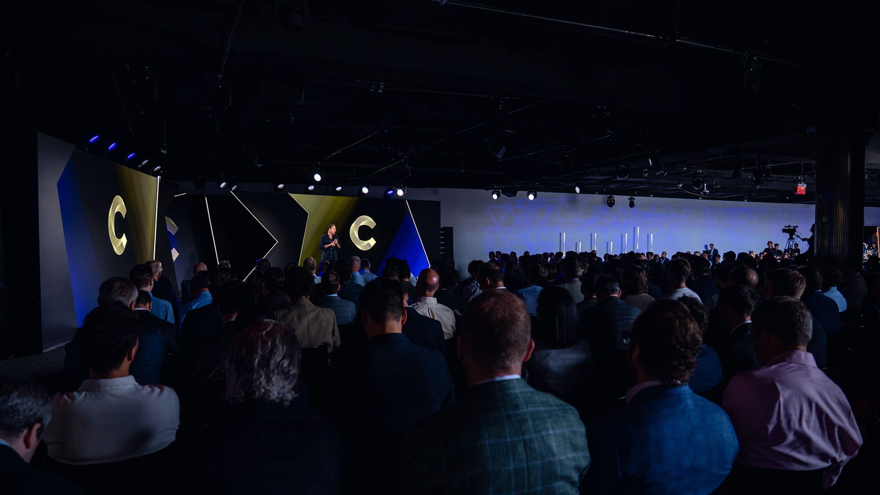 Yuval Rooz on stage in front of a full auditorium at a Canton Network keynote