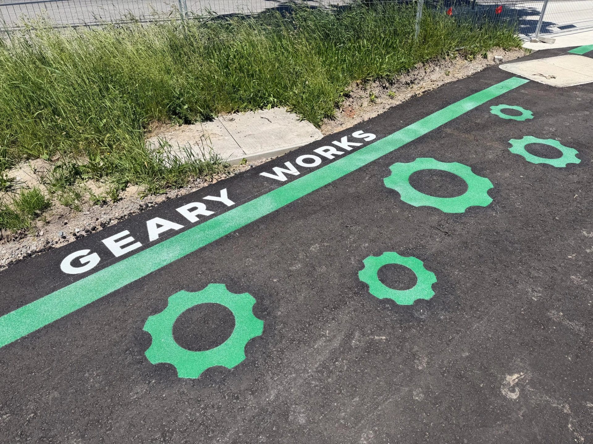 Geary Works lettering and green gear graphics set into an asphalt path