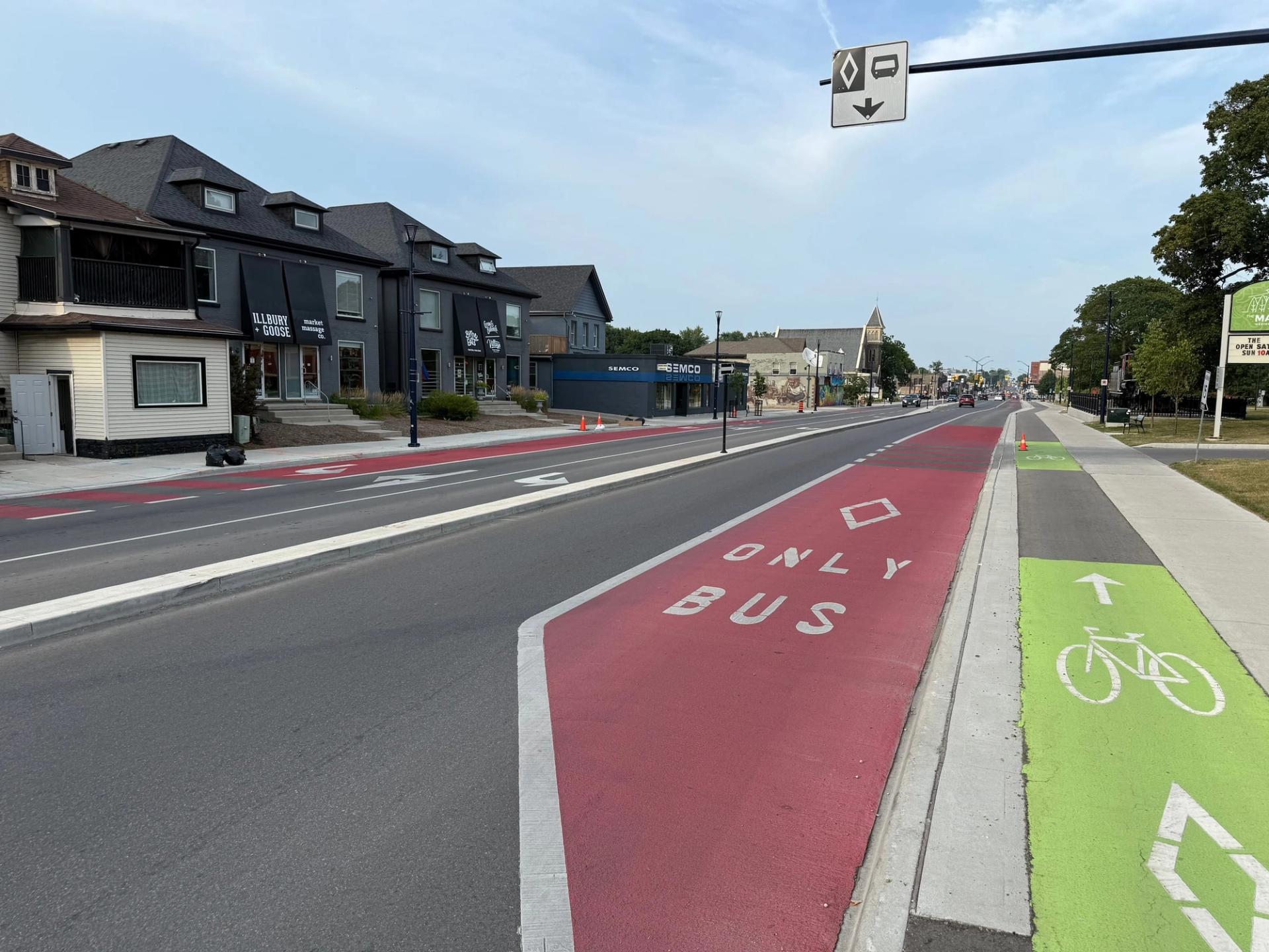 Red bus-only lane with ONLY BUS and diamond legends beside a green bike lane marked with a bicycle symbol and arrow
