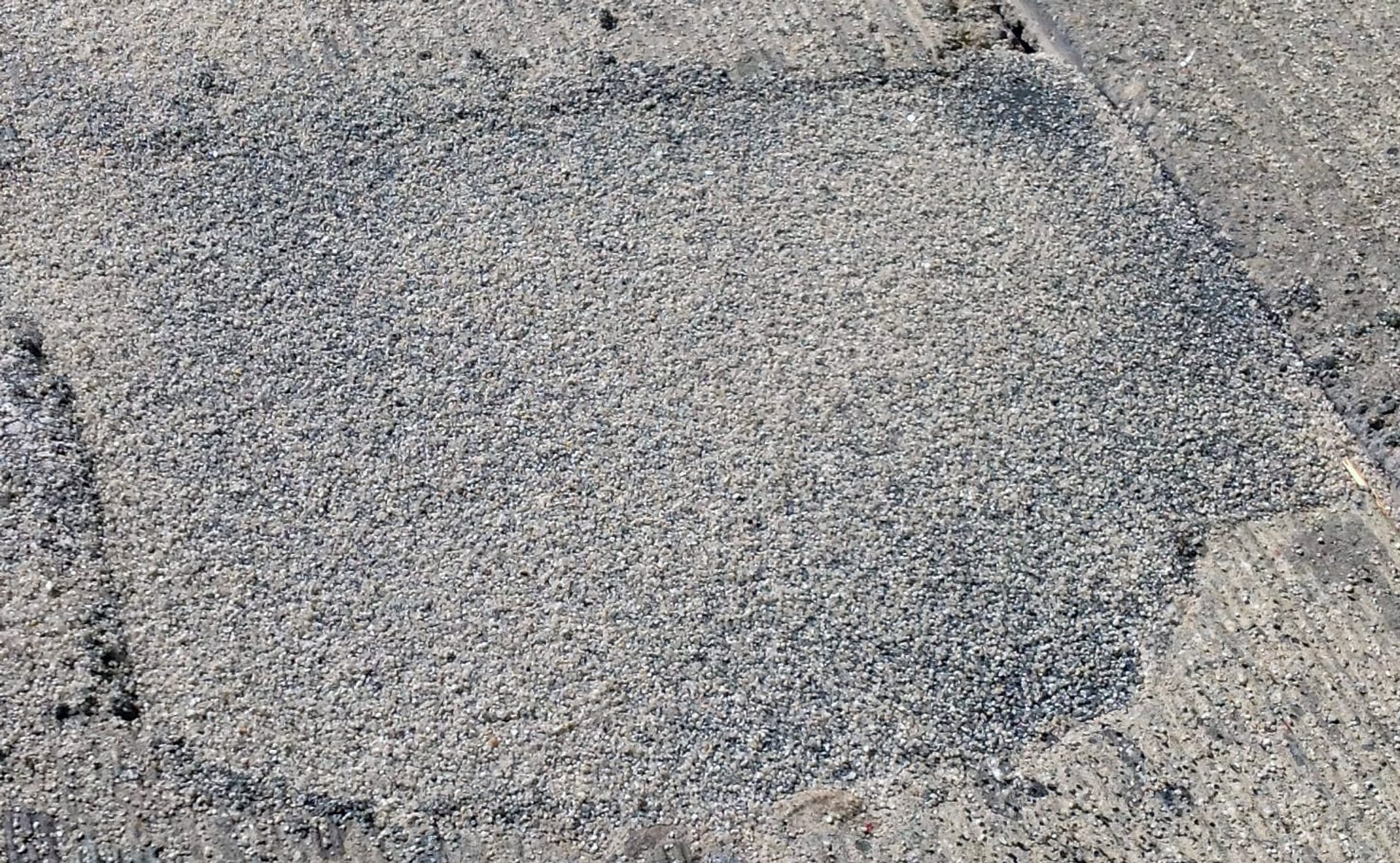 A finished Fast Patch DPR repair, a patch of fine grey aggregate set flush in the surrounding pavement