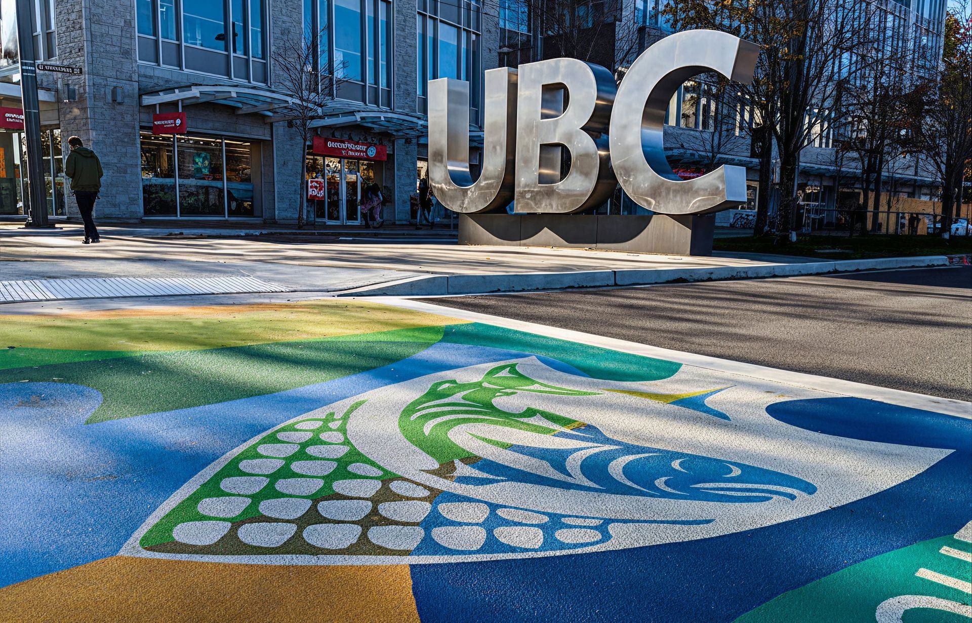 The UBC Musqueam crosswalk at the University of British Columbia campus entrance in Vancouver — Coast Salish artwork rendered in coloured pavement by HUB Surface Systems