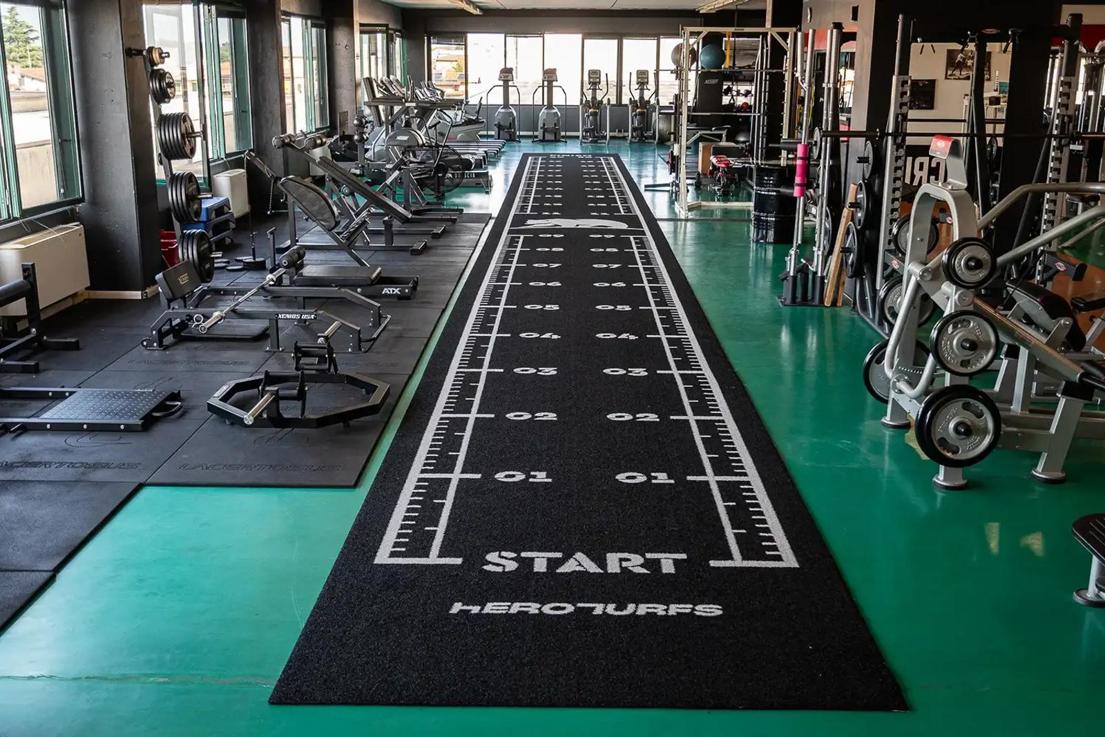 Black sled track contrasting with the green floor of the Move Brescia gym in Bedizzole