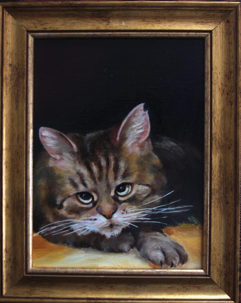 Portret małego pręgowanego kota na ciemnym tle, w złocistej ramie.