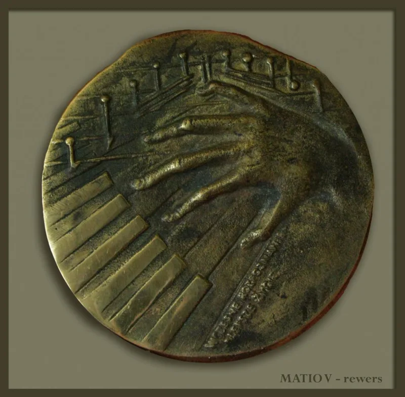 Okrągły medal z dłonią na klawiaturze i drobnymi pionowymi formami w tle.