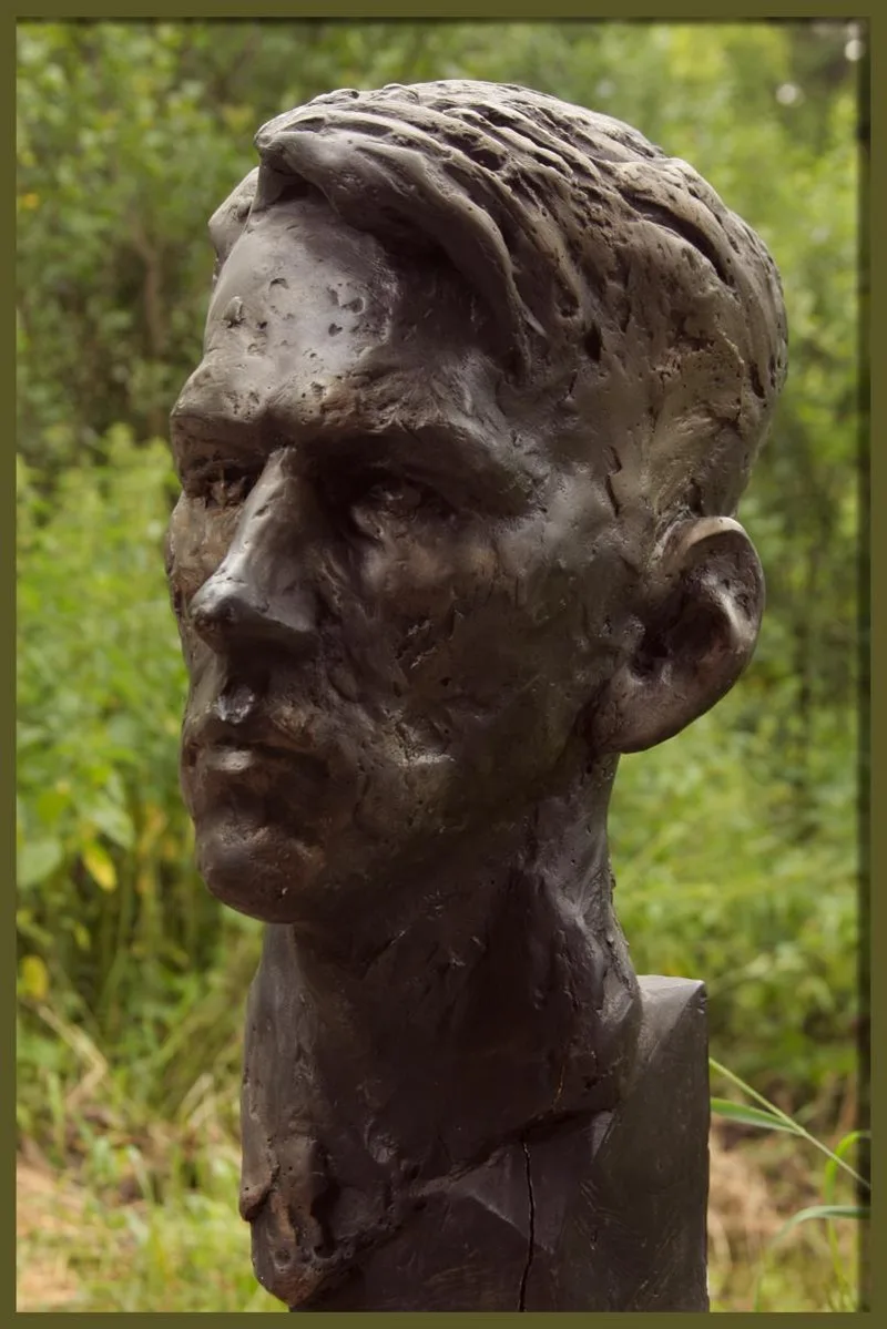 Rzeźbiarski portret młodzieńca na tle zieleni.