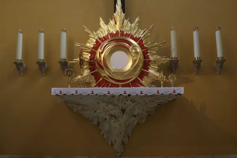 Okrągłe tabernakulum w promienistej oprawie, nad rzeźbioną konsolą i pomiędzy świecami.