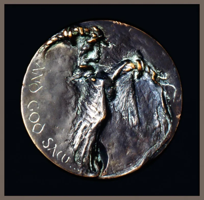 Okrągły medal z wypukłą postacią i napisem „And God saw”.