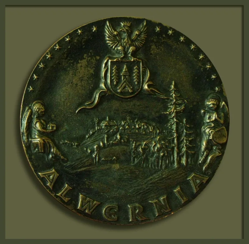 Okrągły medal z napisem „Alwernia”, herbem, architekturą i postaciami po bokach.