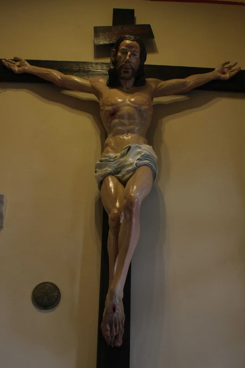 Pełny widok krucyfiksu z barwną figurą Chrystusa na ciemnym krzyżu.