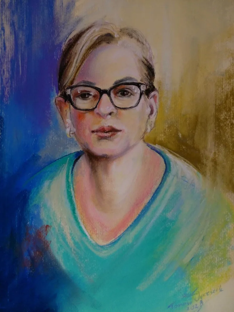 Portret kobiety w okularach i turkusowej bluzce na wielobarwnym tle.