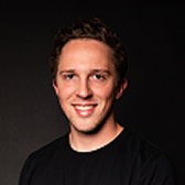 Portrait of Daniel Strangfeld, smiling, in a black t-shirt