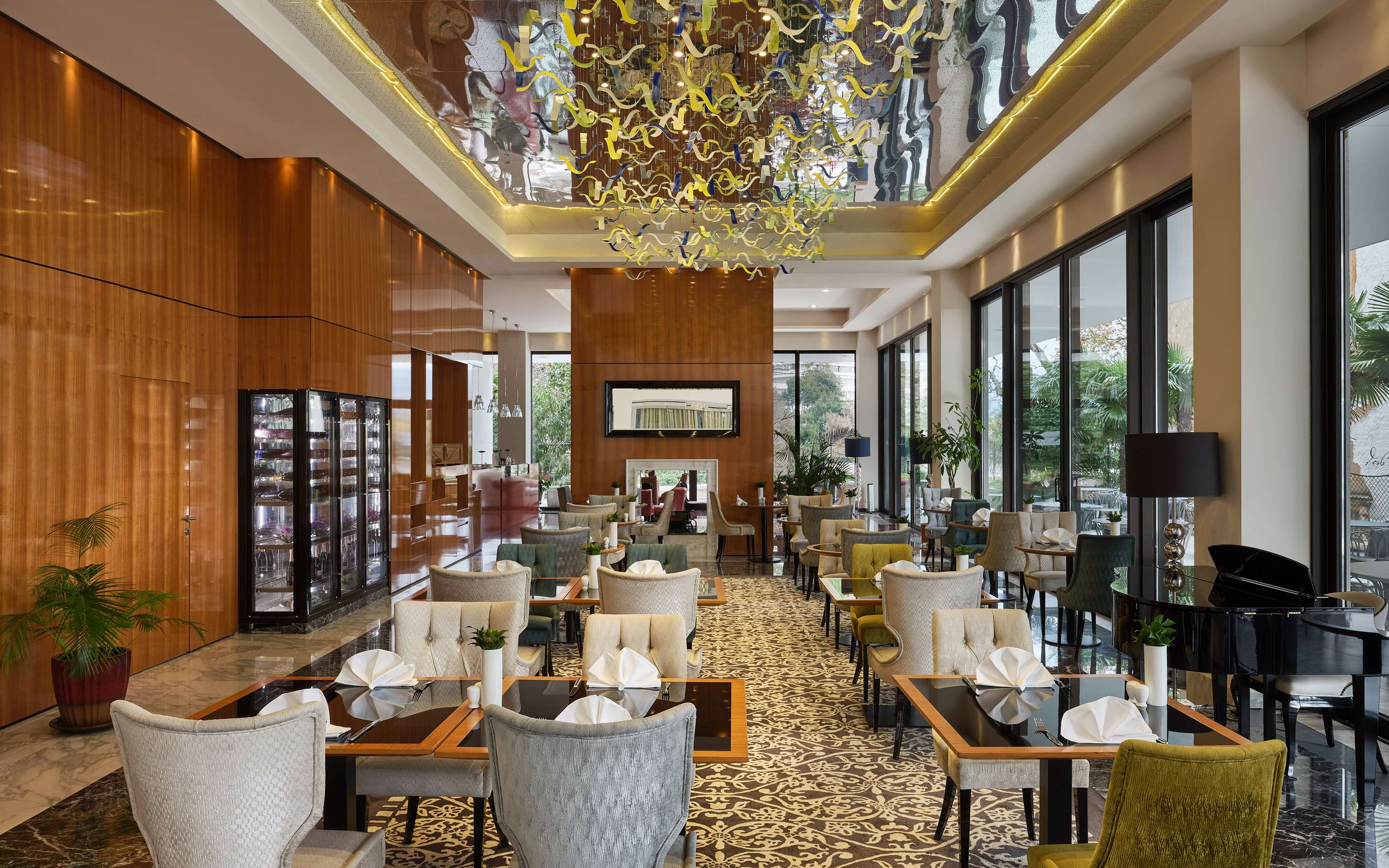 Restaurant Symphonie u Hotelu Royal: postavljeni stolovi pod zlatnim lusterom i visoki prozori prema vrtu