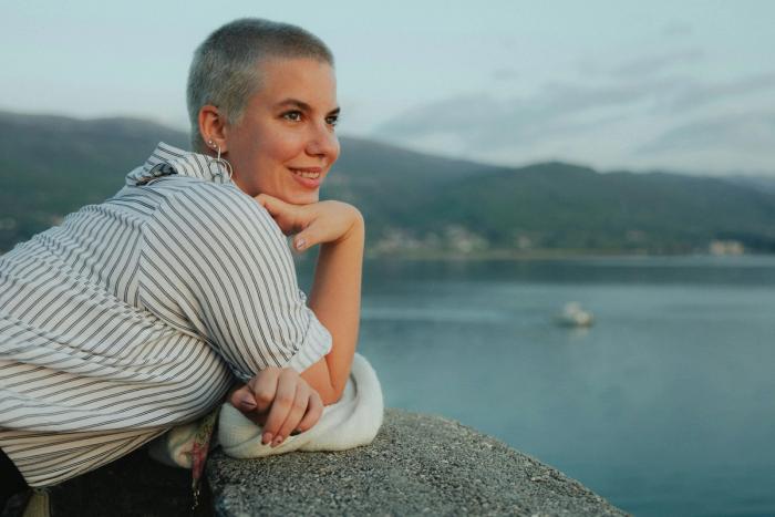 A woman who has completed cancer treatment, calm and smiling lookimg at the view