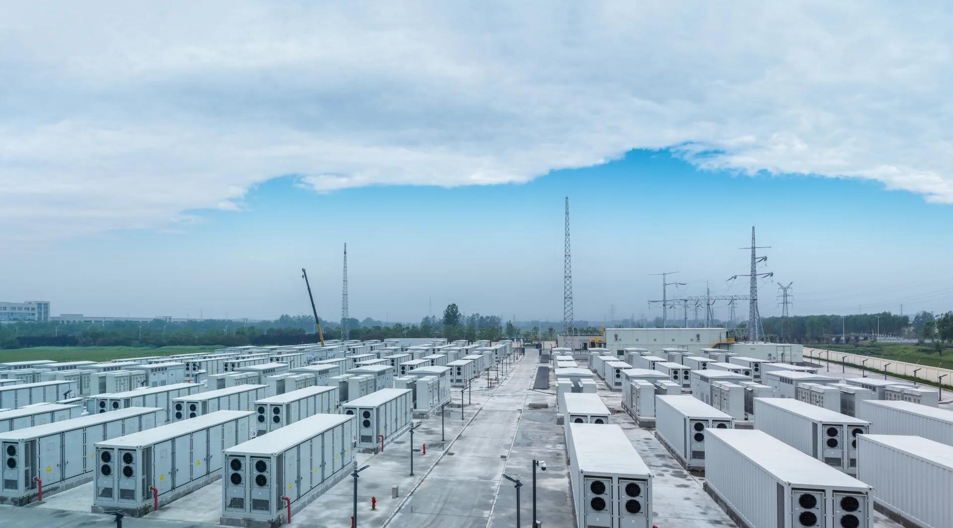 Rows of white battery energy storage containers at a grid-connected storage facility