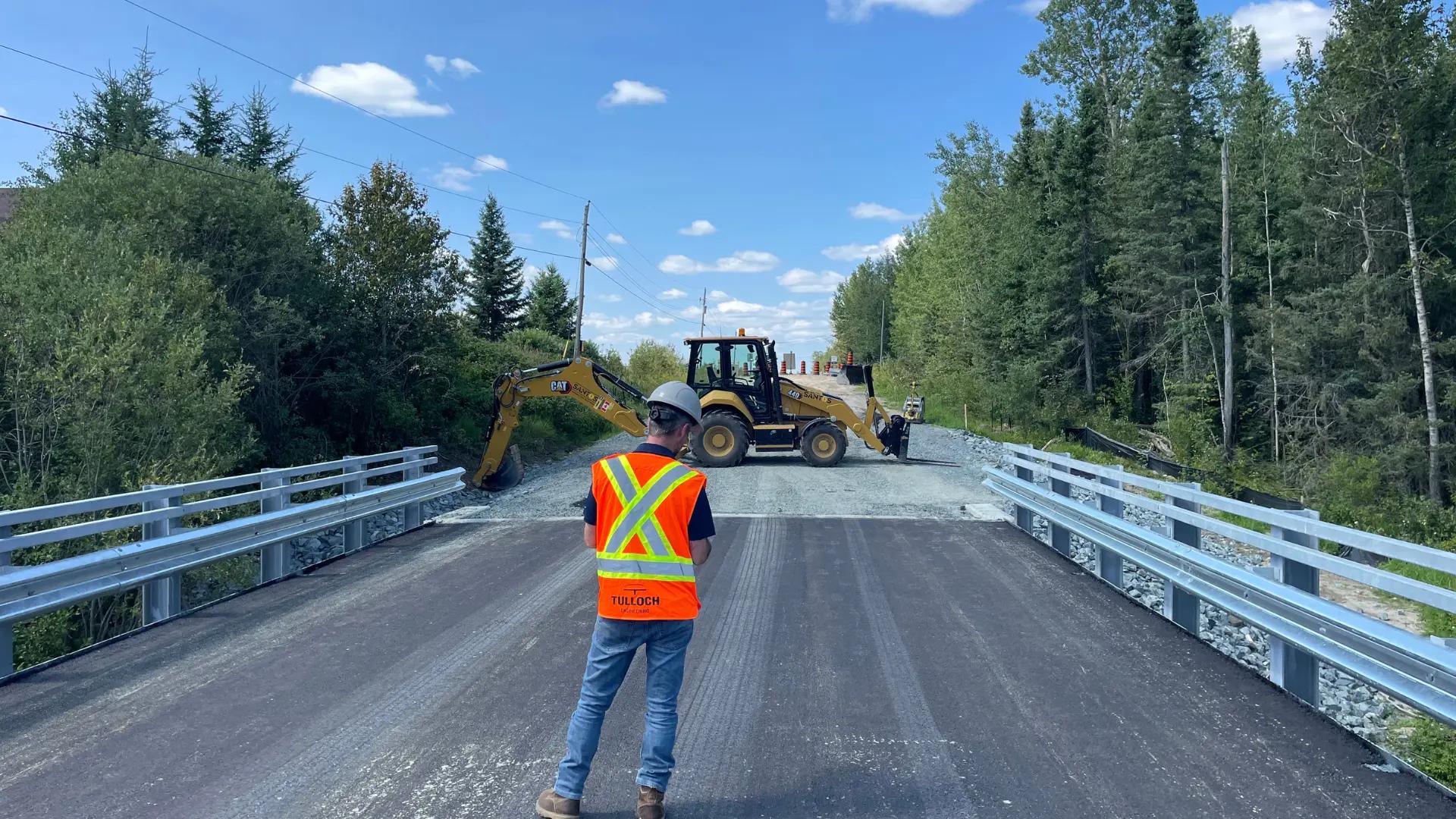 TULLOCH field technician completing a bridge inspection on a roadway.