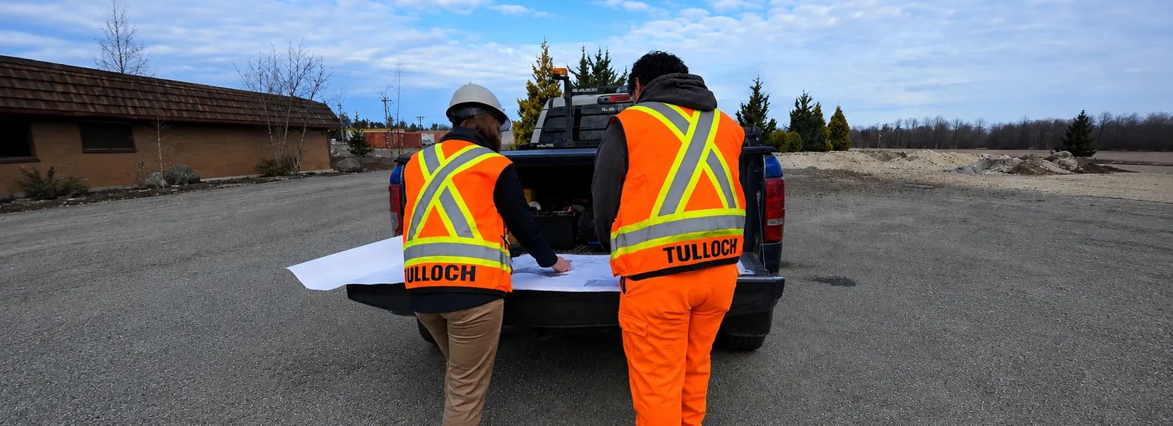 Two technicians reviewing plans on truck tailgate.