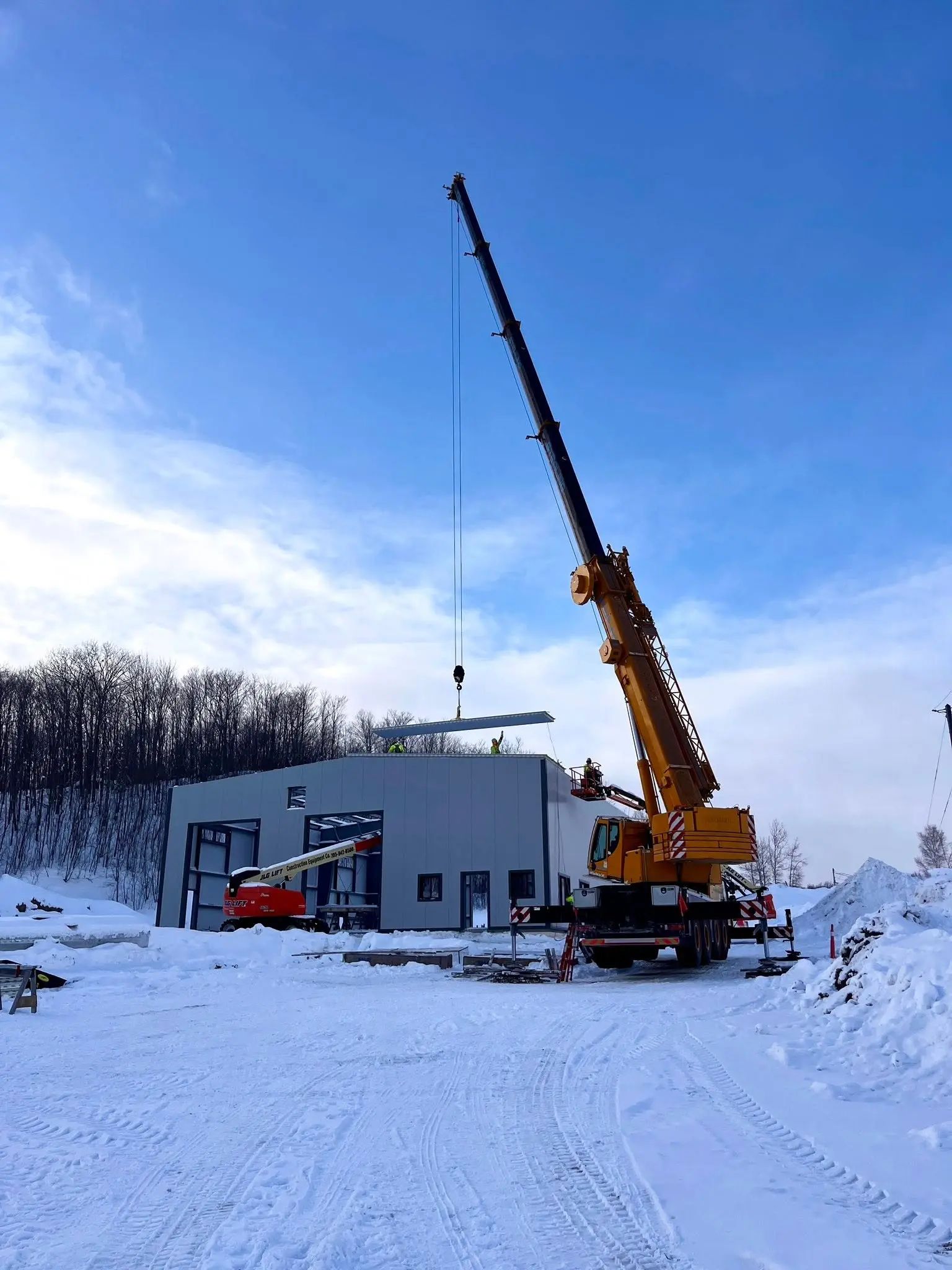 Crane working beside a new industrial or municipal building during winter construction.