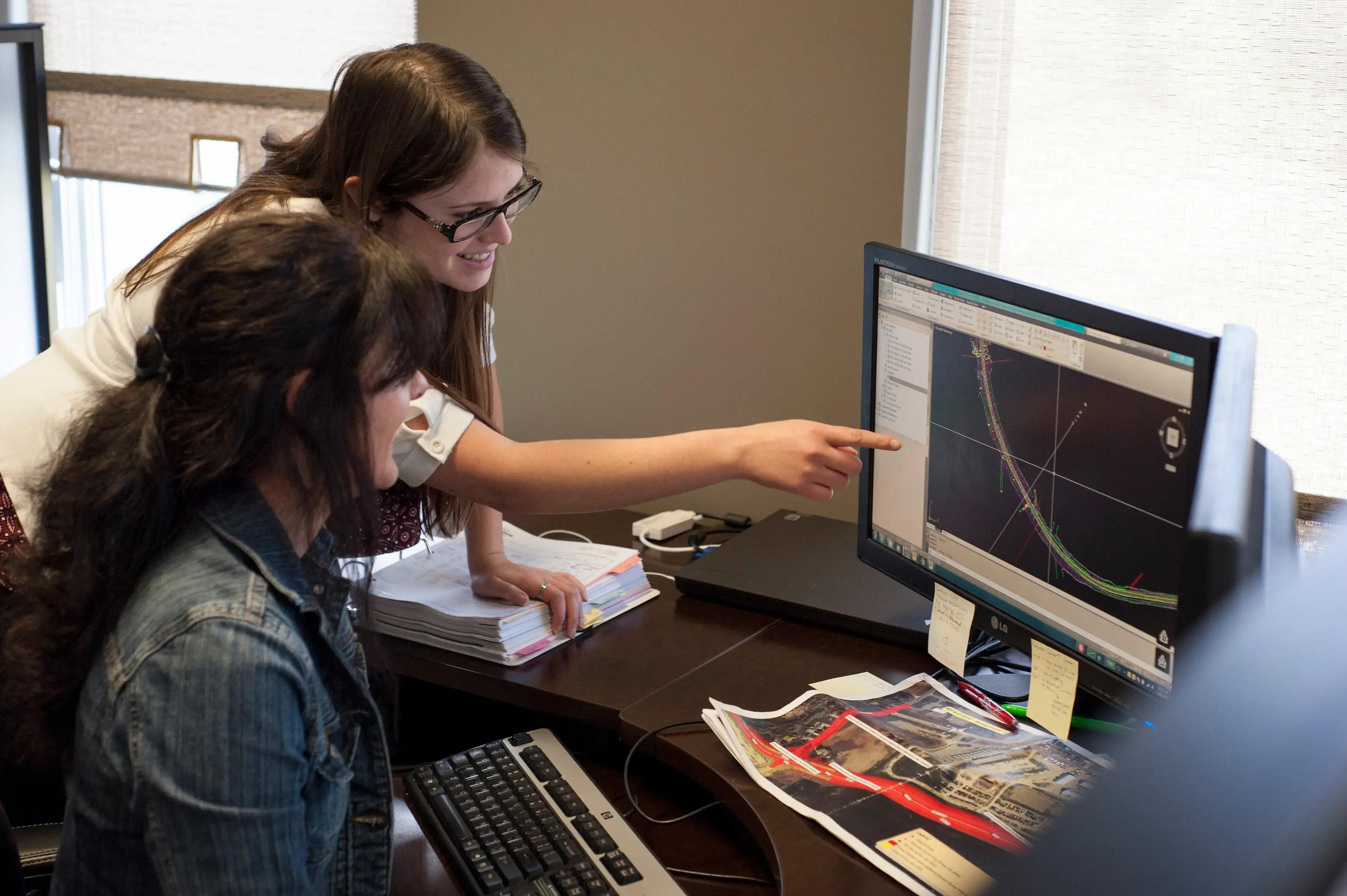 TULLOCH team members collaborating around mapping data on a computer.