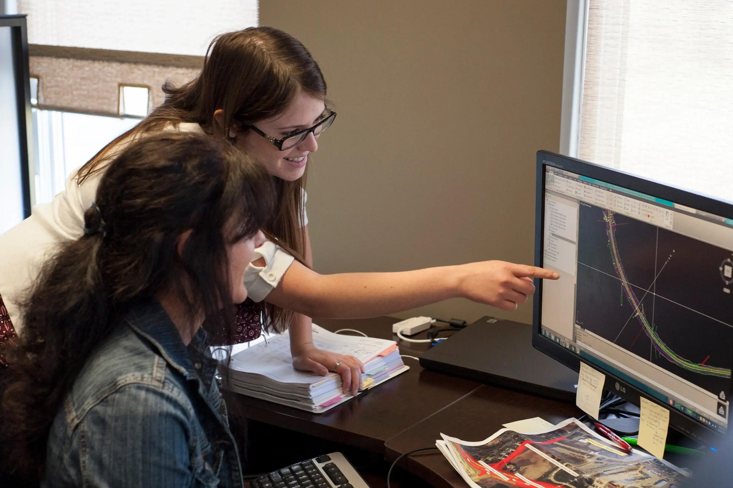 TULLOCH team members collaborating around mapping data on a computer.