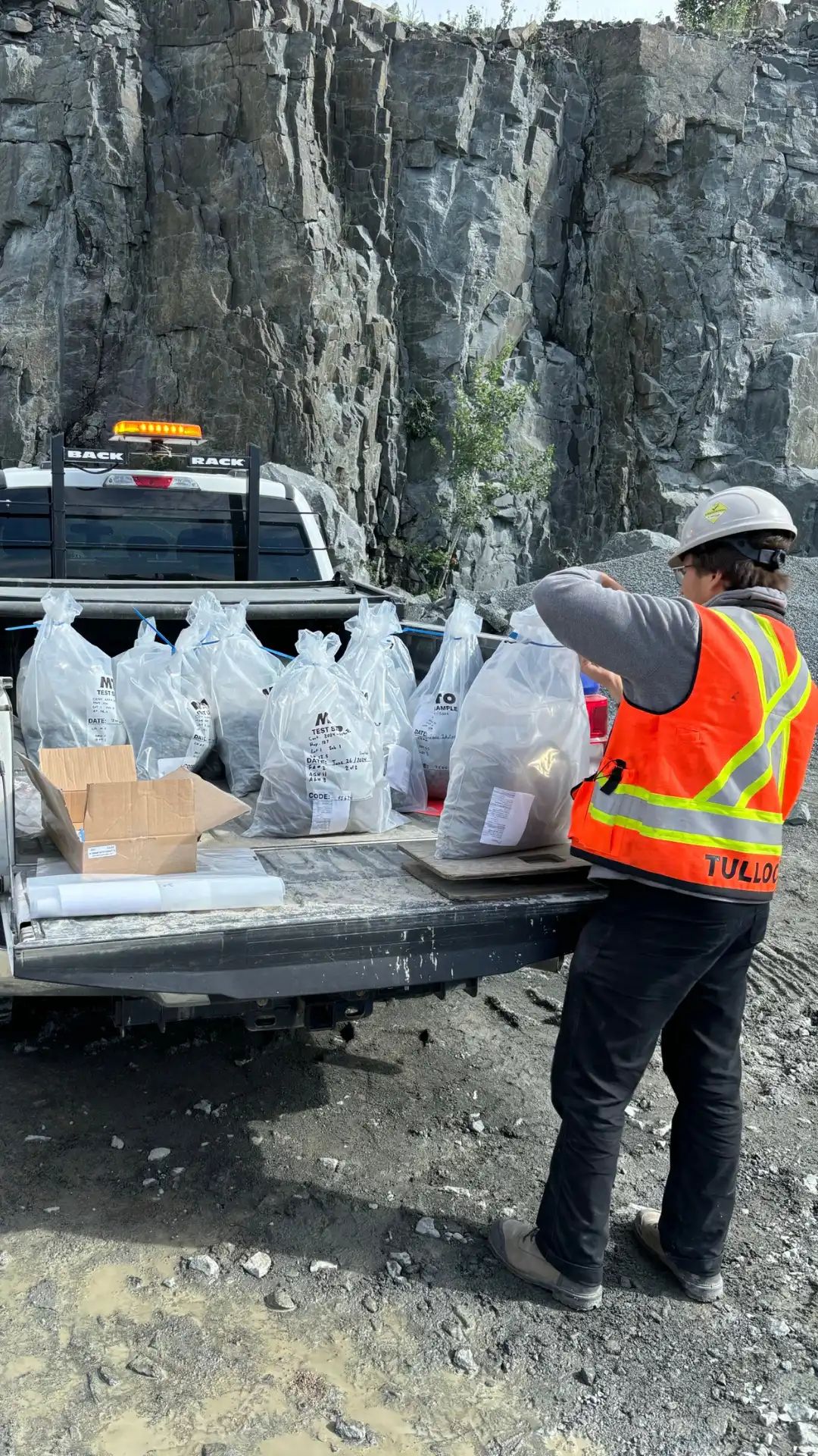 TULLOCH geotechnical field technician working beside a rock cut and company truck.