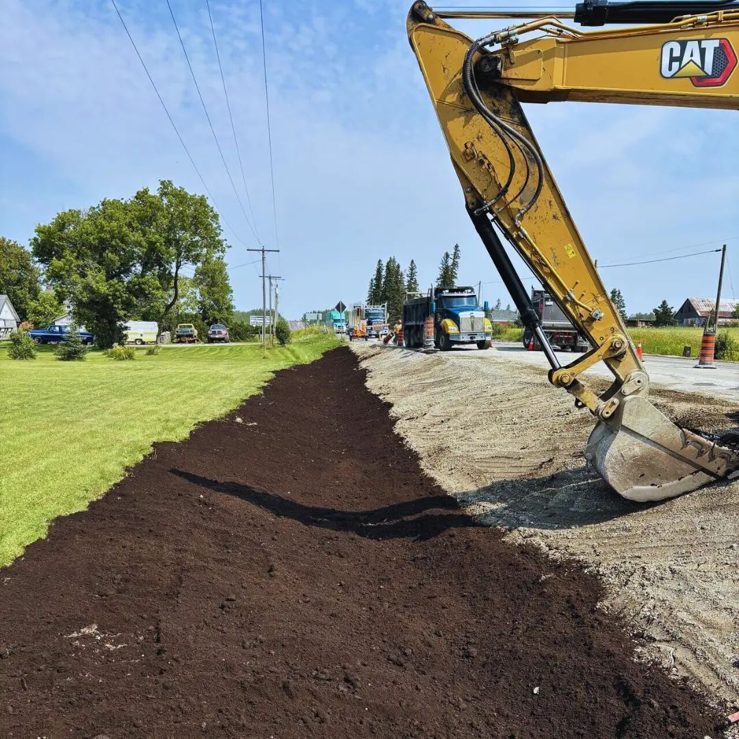 Excavator completing roadside excavation and grading work.