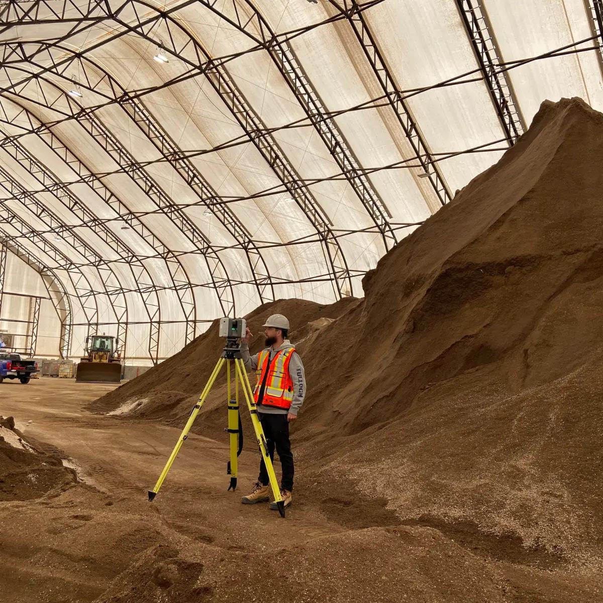 TULLOCH survey technician measuring a large indoor material stockpile.