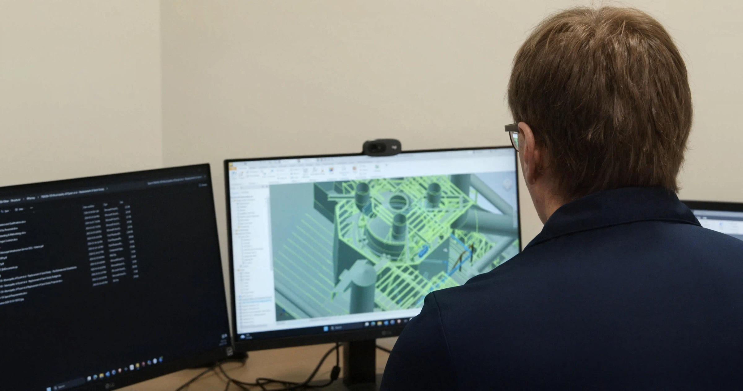 Mechanical engineering reviewing a 3D model at computer.