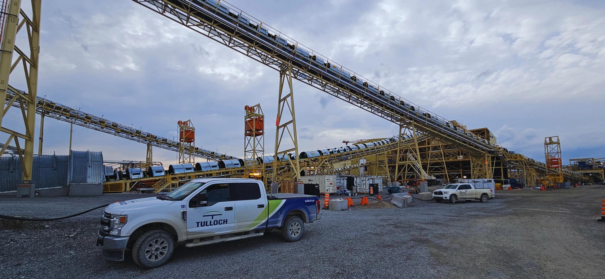 TULLOCH company truck beside conveyor infrastructure at an industrial site.