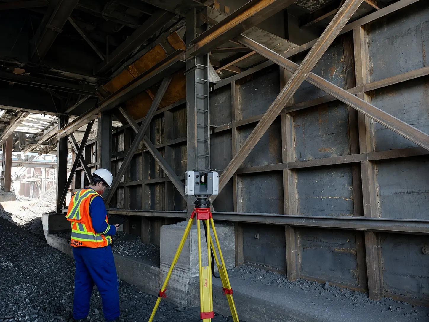 TULLOCH surveyor operating a total station beneath an industrial structure.