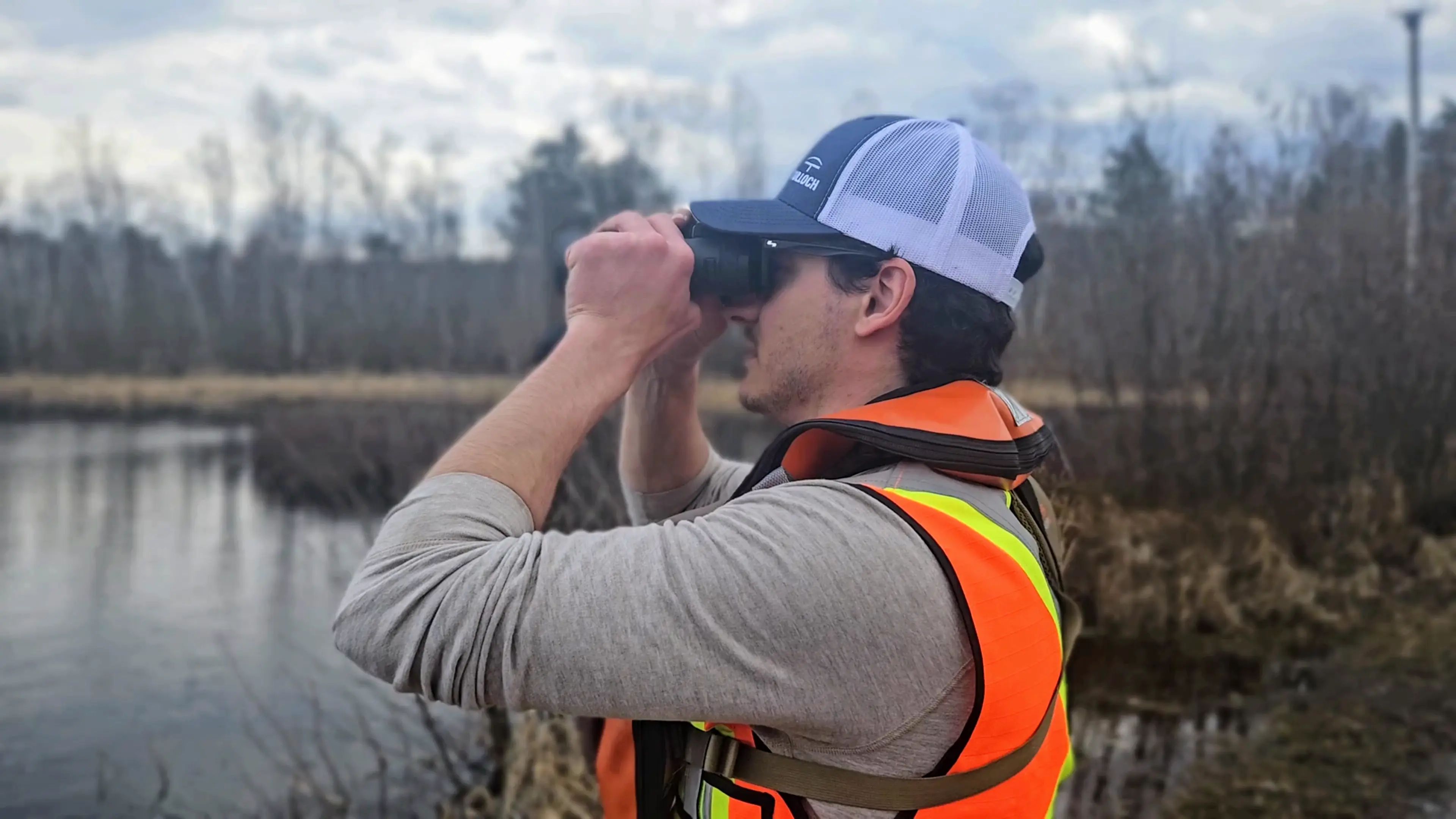 TULLOCH environmental field technician using binoculars during a wildlife survey.