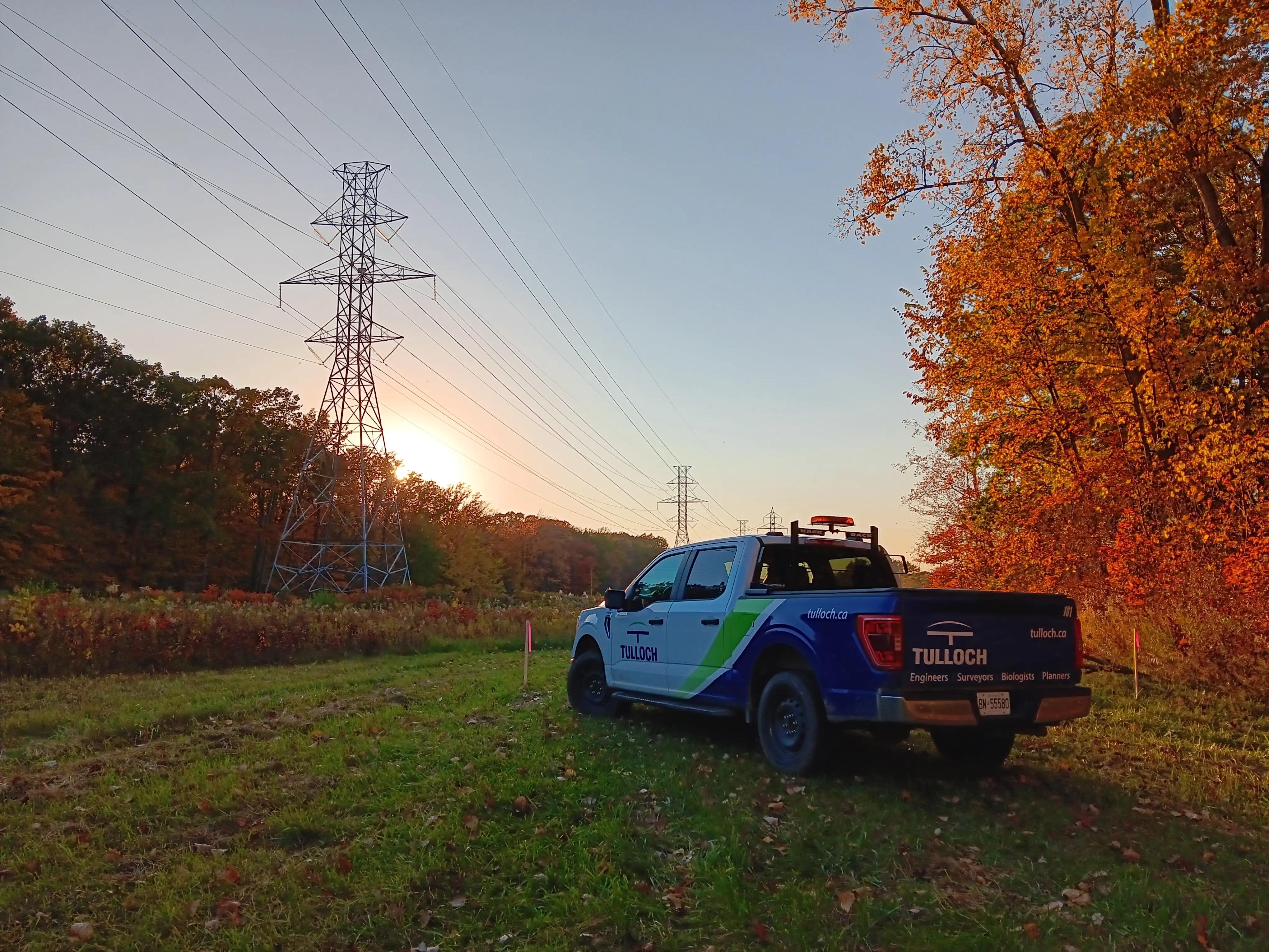 TULLOCH company truck beneath transmission lines in the evening.