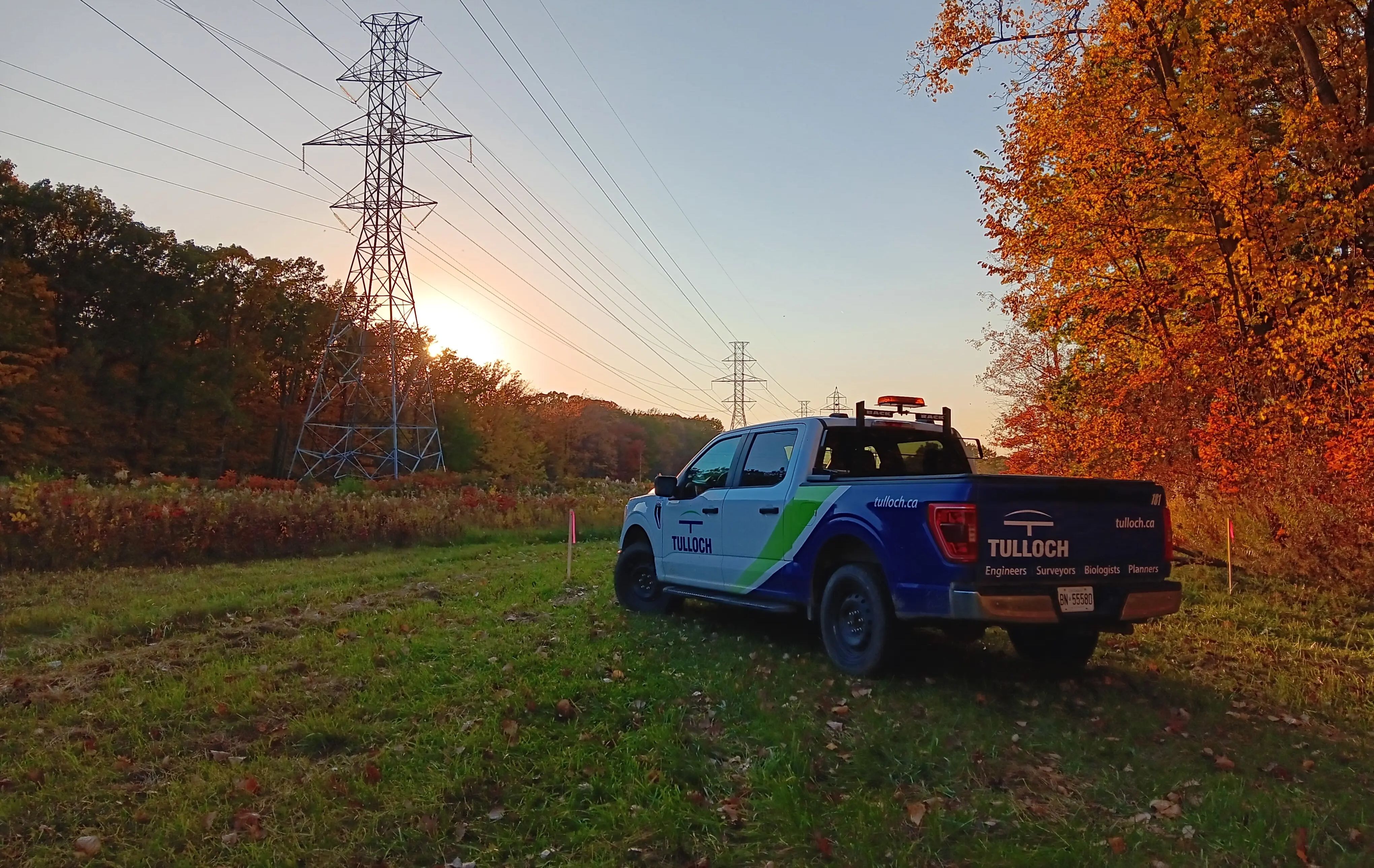 TULLOCH company truck beneath transmission lines in the evening.