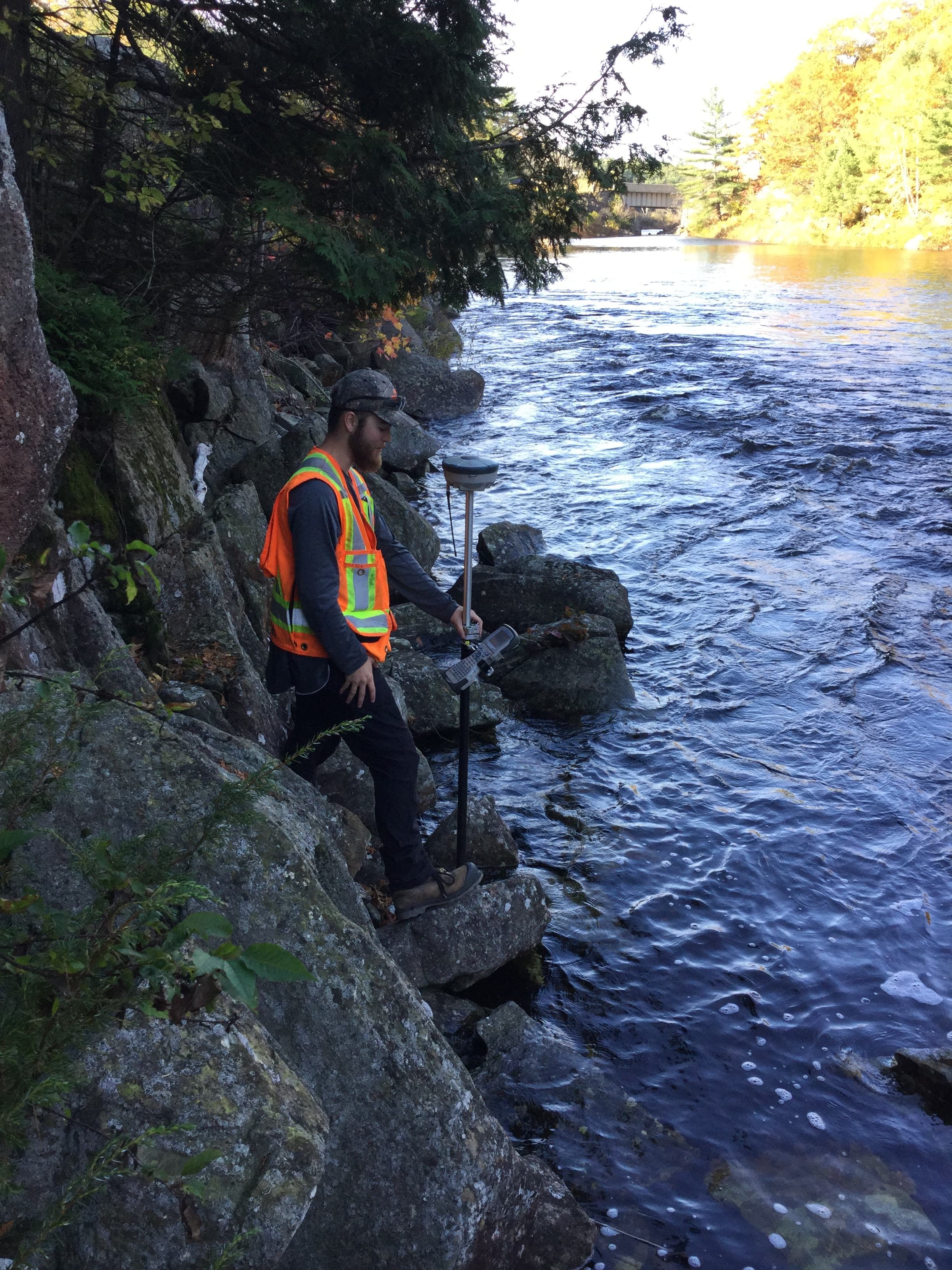 TULLOCH environmental field technician completing monitoring beside a stream at Henvey Inlet.