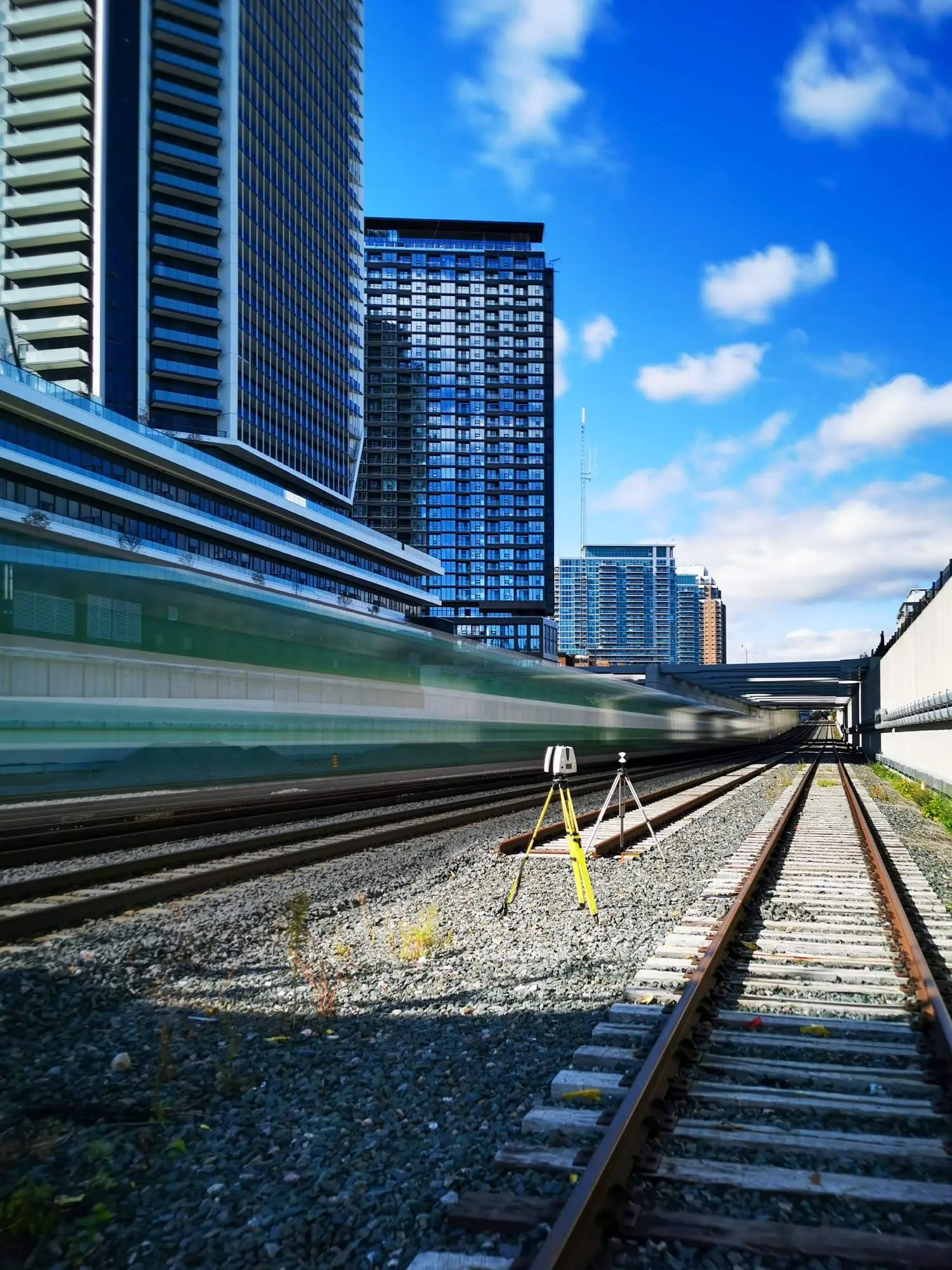 Survey equipment positioned beside an urban rail corridor.