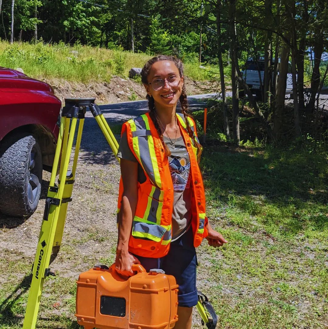 TULLOCH land surveyor standing beside survey equipment in the field.