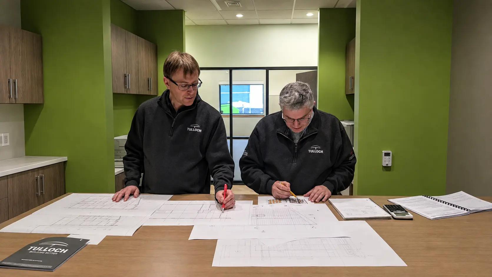 Heavy industry engineering team reviewing drawings in office.