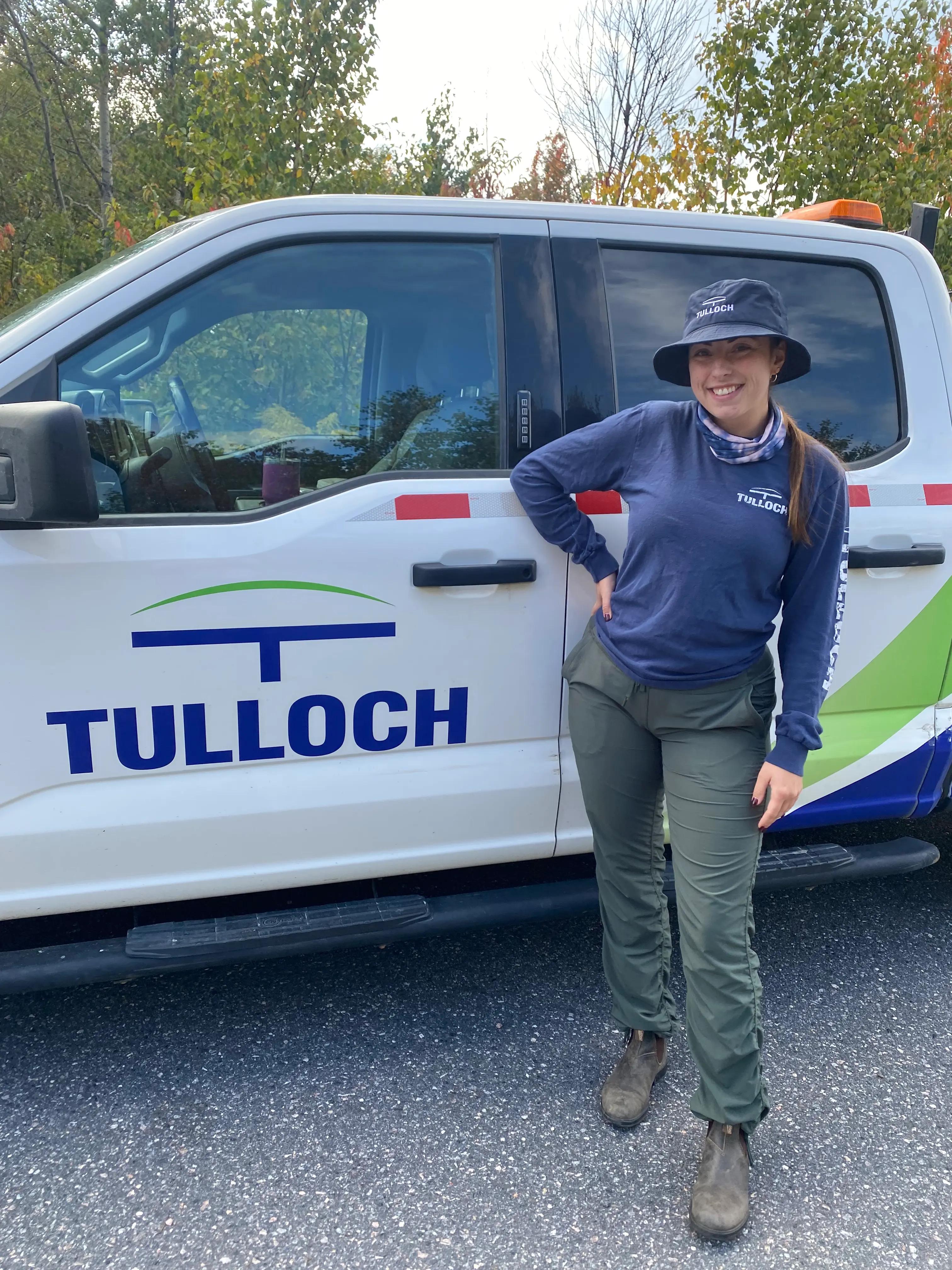 Environmental technician smiling in front of TULLOCH truck.